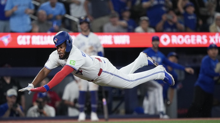 Le joueur de premier but des Blue Jays de Toronto Vladimir Guerrero fils (27) marque un point devant le receveur des Red Sox de Boston, Adley Rutschman (non visible), lors de la huitième manche d'un match de baseball de la Ligue américaine de la MLB à Toronto le mercredi 12 août 2026.