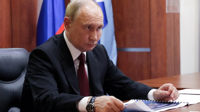 Vladimir Poutine est assis à un bureau.
