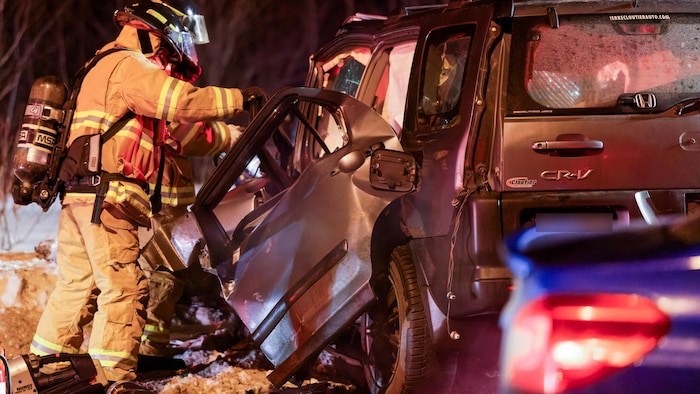 Un pompier près d'un véhicule accidenté.