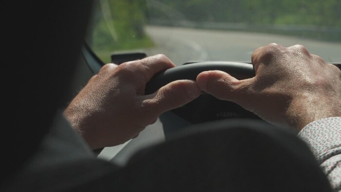 Deux mains tiennent le volant d'une voiture.