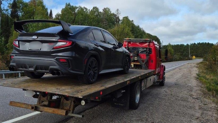 Une voiture sur une plate-forme d’une remorqueuse.