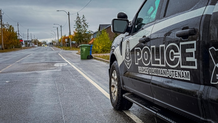 Une voiture de police stationnée sur le côté de la rue sous la pluie.