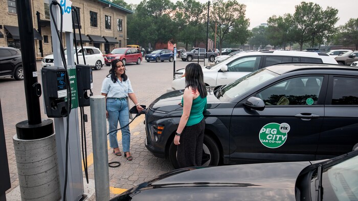 Deux femmes autour d'une voiture électrique.