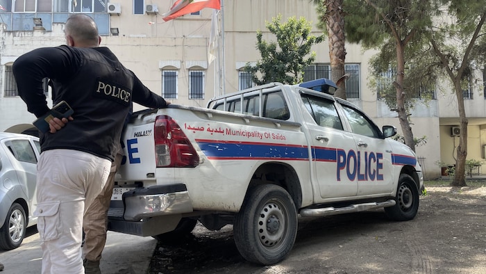 Un agent s'appuie sur une voiture de police.