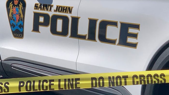 Logo sur le côté d'une voiture et cordon policier jaune. 