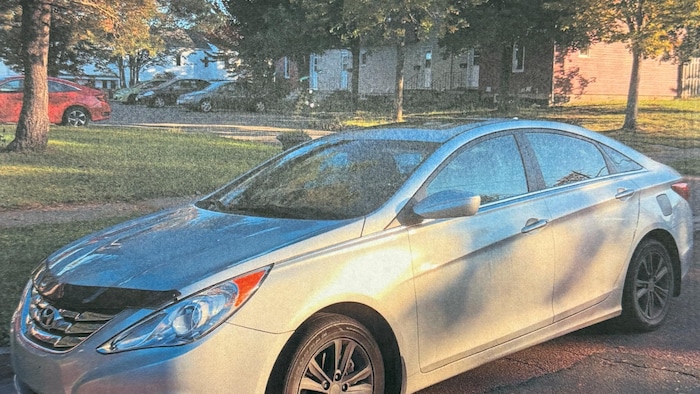 Une photo granuleuse d'une voiture grise.
