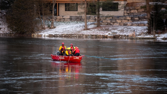 Des pompiers font des recherches sur un bateau sur la rivière Magog.