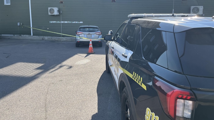 Un véhicule de police surveille une voiture dans un périmètre de sécurité. 