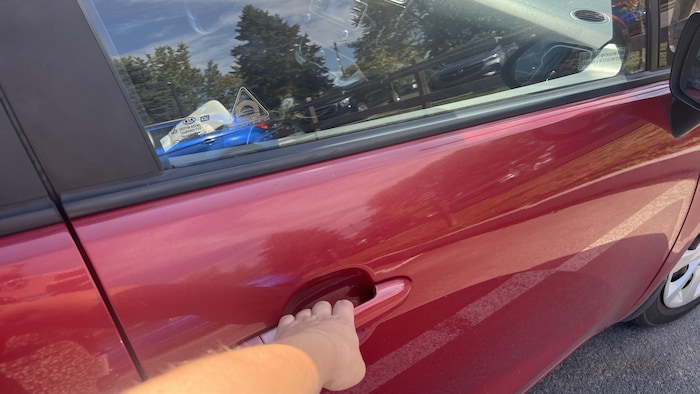 Une main ouvre une porte d'auto.