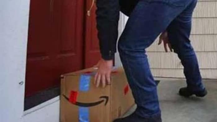 Un homme encagoulé ramasse un colis Amazon sur le pas de porte d’un domicile. Il semblerait que ce soit un voleur.
