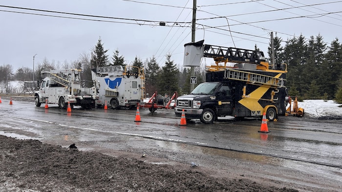Un camion de Bell et un camion de Videotron sont stationnés près d'un poteau électrique. Des cônes délimitent le secteur.