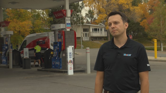 Sam Babcock se tient debout dans une station-service Mobil.