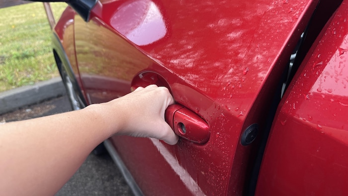 Un personne ouvre une portière de voiture. 