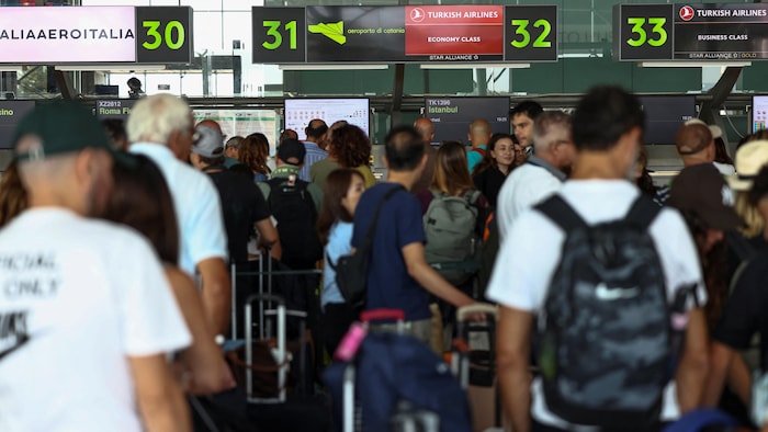 Des passagers attendent à l'intérieur du terminal de l'aéroport.