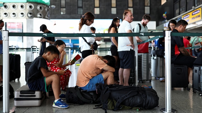 Des passagers attendent à l'intérieur du terminal de l'aéroport.