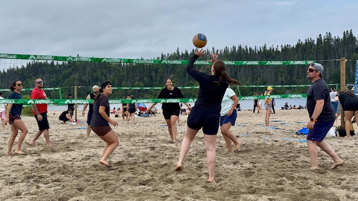 Une personne reçoit la balle durant un match de volleyball. Les autres joueurs regardent l'action et se tiennent prêts.