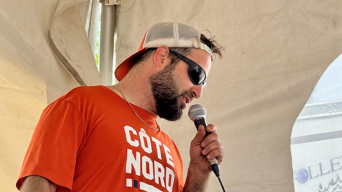 Yannick Bouchard parle au micro sous la tente de l'organisation du tournoi.