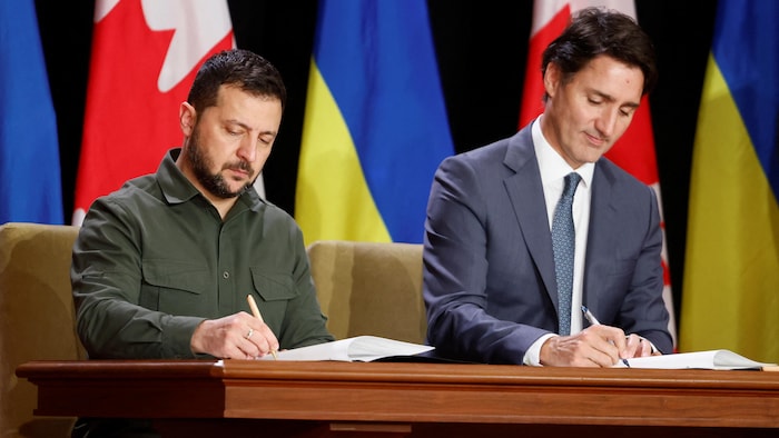 Le premier ministre canadien, Justin Trudeau, signe des documents aux côtés du président ukrainien Volodymyr Zelensky.