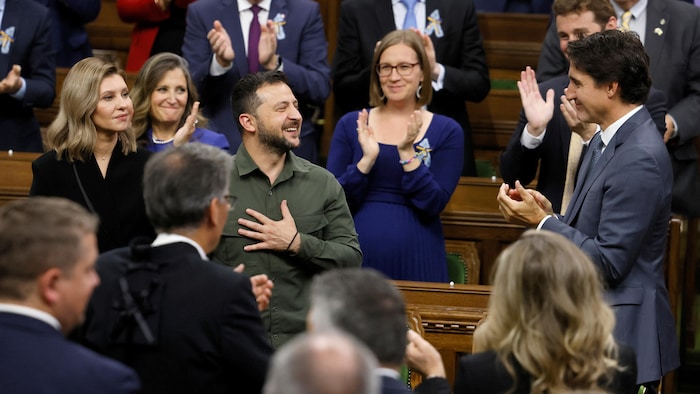 Volodymyr Zelensky, souriant et la main sur le coeur, applaudi par les députés et Justin Trudeau.