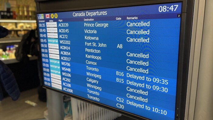 Un écran sur les départs de vols à l'aéroport de Vancouver montre plusieurs vols annulés et d'autres retardés.