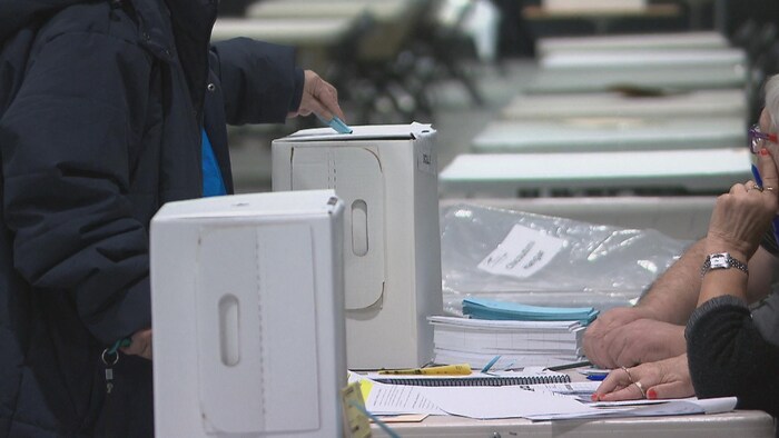 Un électeur dépose son bulletin de vote dans une urne.