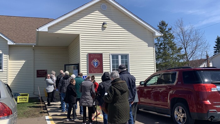 Des personnes font la file à l'extérieur d'un bureau de scrutin. 