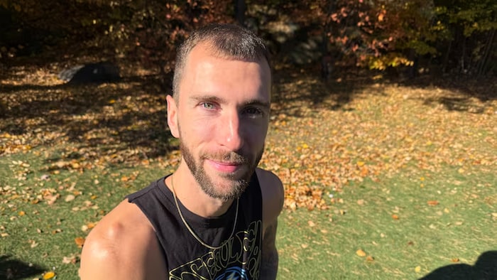 Un homme se fait photographier dans un parc, alors que les feuilles commencent à tomber à l'approche de l'automne.