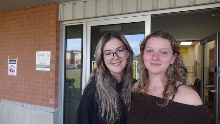 Portrait de deux jeunes filles devant l'entrée du bureau de vote.