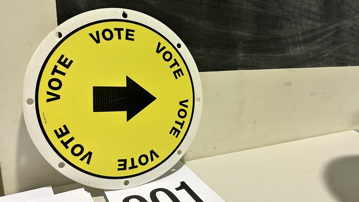 Une affiche avec une flèche qui indique où aller voter.