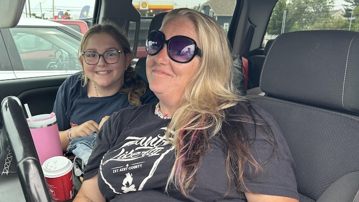 Une femme et sa fille sont photographiées dans leur voiture.