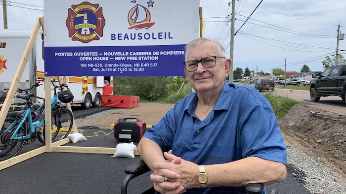 Un homme assit dehors les mains croisées.