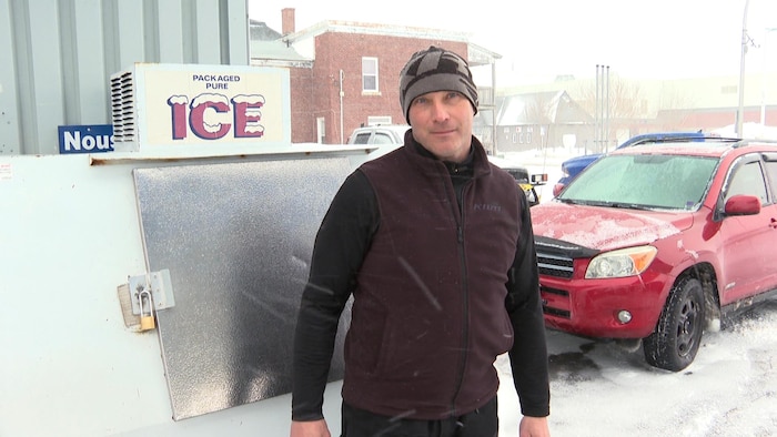 Un homme dans une forme physique exemplaire est dehors devant une machine à glace pendant une tempête de neige.