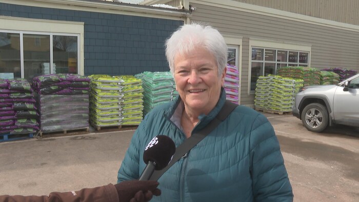 Une femme dans un stationnement avec un micro pointé en sa direction.