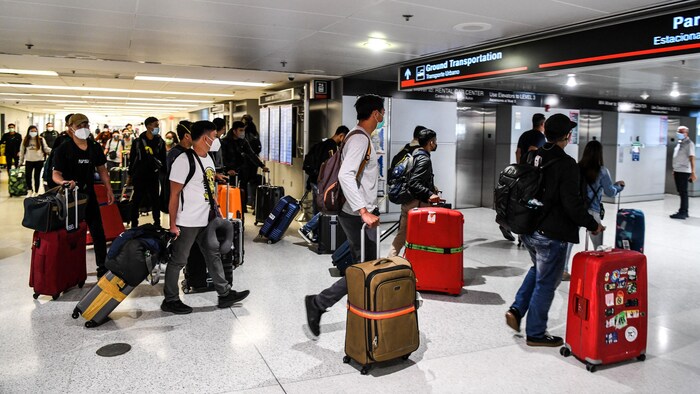 Des voyageurs arrivent à l'aéroport international de Miami.