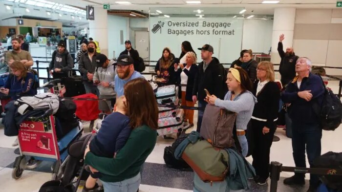 Des voyageurs font la queue devant le comptoir de WestJet dans l'aéroport de Toronto.
