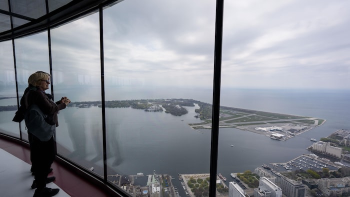 Le 13 mai 2026, des visiteurs contemplent l’aéroport de l’île de Toronto depuis la plateforme d’observation de la Tour CN.