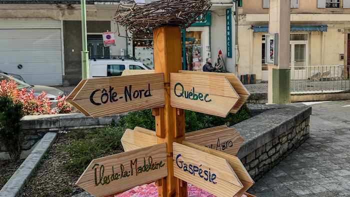 Un poteau en bois avec des flèches où sont inscrites les noms de régions du Québec.