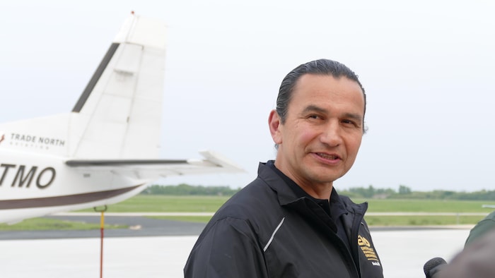 Wab Kinew parle aux médias devant un hélicoptère sur le tarmac de l'aéroport de St. Andrews. (12 juin 2025)