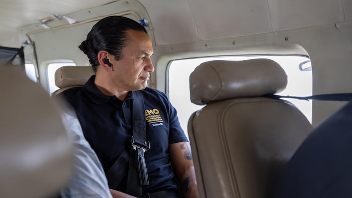 Le premier ministre du Manitoba, Wab Kinew, regarde par la fenêtre d'un avion lors d'une tournée pour voir les feux de forêt qui sévissent dans le nord du Manitoba, le 12 juin 2025.