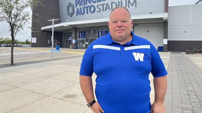 Wade Miller porte un polo des Blue Bombers de Winnipeg, devant le stade Princess Auto.