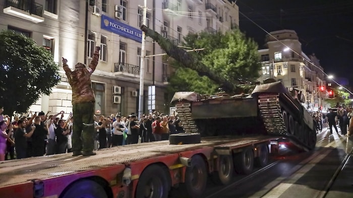Un tank est chargé sur la remorque d'un camion sous les regards de la foule.