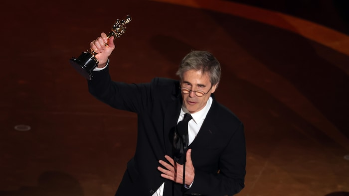 Un homme brandit son trophée en l'air sur scène. 