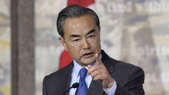 Wang Yi répond sévèrement à une journaliste, l'index levé.