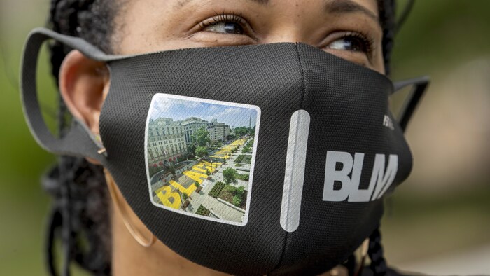 Shawna Jacobs porte un masque avec une photographie de la 16e rue nord-ouest rebaptisée Black Lives Matter Plaza près de la Maison-Blanche, le vendredi 19 juin, à Washington.