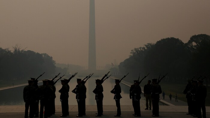Des soldats se tiennent au garde-à-vous sur l'esplanade remplie de brouillard.