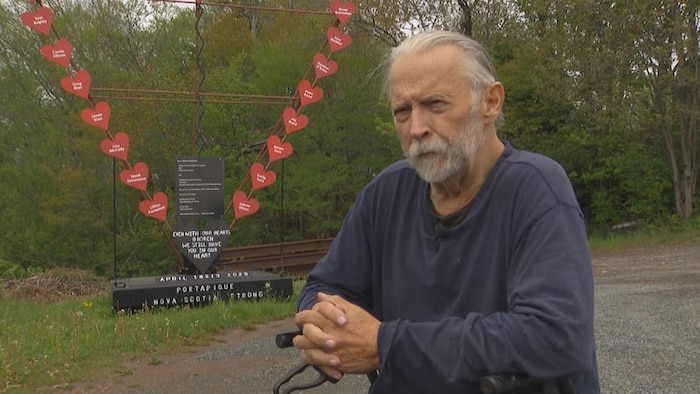 Wayne Smith devant un monument en hommage aux victimes. 