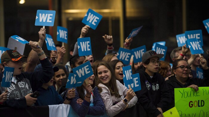 Des dizaines d'adolescents tiennent des affiches sur lesquelles on peut lire « We ».