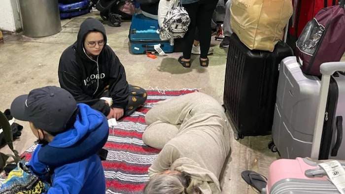 Passengers await transport at the airport in Cancun, Mexico, in the early hours of Christmas Day, after their delayed flight home to Canada was cancelled. (Hina Itsaso/Handout photo/The Canadian Press)