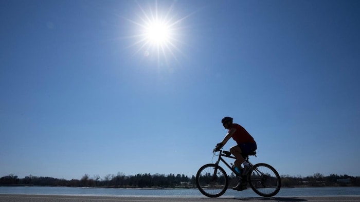Un cycliste pédale sur un chemin sous le soleil par une chaude journée.