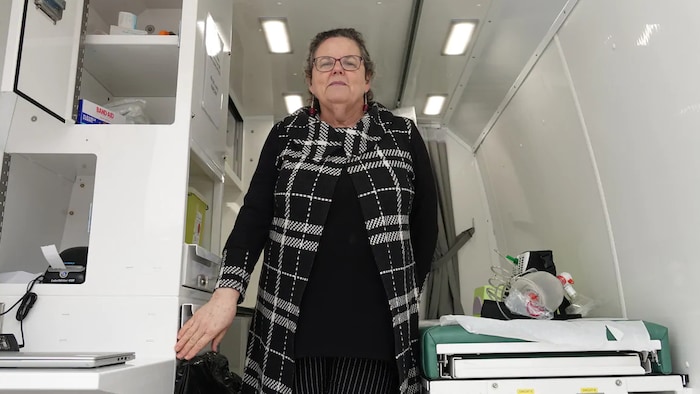 Wendy Muckle pose pour la caméra debout dans une fourgonnette modifiée en petite salle d'examen médical.  